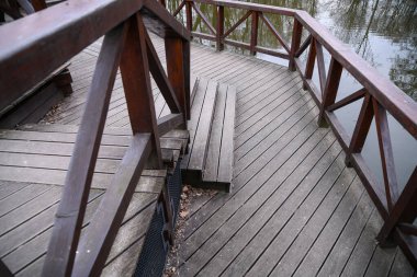 Köprüde çapraz demirleri ve ahşap güvertesi olan kahverengi ahşap korkuluklar var..