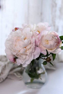 Fotoğraf, şeffaf cam bir vazoda duran zarif pembe şakayık buketini gösteriyor..