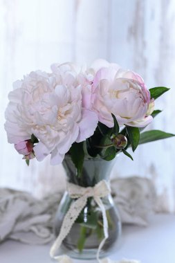 Fotoğraf, şeffaf cam bir vazoda duran zarif pembe şakayık buketini gösteriyor..