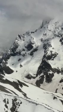 Kar kaplı tepeler ve ufuk boyunca uzanan dağlar.