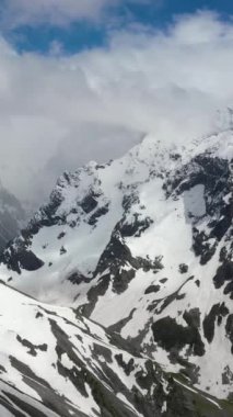 Kış mevsiminde tepeleri yuvarlanan karlı dağ sıraları.