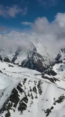 Parlak kış güneşi altında karla kaplı tepelerin havadan görünüşü.