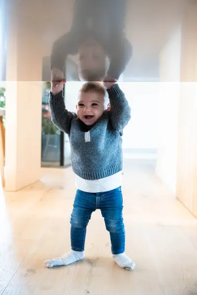 Bir bebek, büyümede erken bir dönüm noktasına ulaşırken harika bir kararlılık, odaklanma ve güç göstermek için bir masaya tutunur..