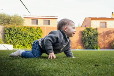Bir bebek taze yeşil çimenlerin üzerinde emekler doğayı neşe merakı ve çocukluk masumiyeti ile keşfederek.