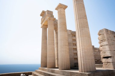 Klasik Yunan tapınağından güçlü taş sütunlar, muhtemelen Doriç tarzında, güneş ışığıyla yıkanmış ve Akdeniz 'in zemininde dimdik ayakta duruyor..