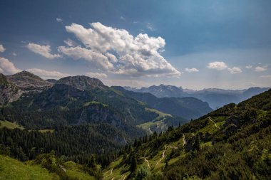 Mavi bulutlu gökyüzünün altında dağları olan yeşil tepelerin güzel manzarası.