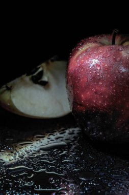 Siyah arka planda su damlaları olan kırmızı elma. Yakın plan.