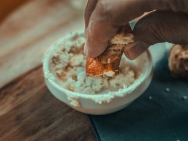 Bir krakerle peynir yiyen birinin yakın plan fotoğrafı.