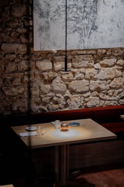 Üzerinde lamba ve vazo olan bir masa. Masa, üzerinde resim olan bir duvarın önünde.