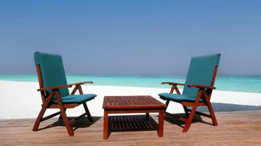 İki boş sandalye, berrak gökyüzü ve sakin mavi su ile sakin bir sahil tatili.