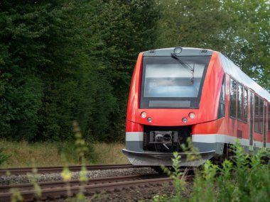Tramvay yeşil arazide ilerliyor.