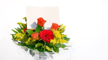 Beyaz arka planda hediye kartı olan bir buket taze çiçek..