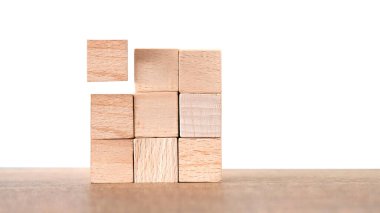 Ahşap bloklar bir masa yüzeyinde düzgün bir şekilde dizilmiş, bir blok yukarıda yükselmiş, organizasyon, yaratıcılık ve minimalist tasarım ilkeleri vurgulanıyor. İnşaat, ilerleme ve yapı için bir metafor.