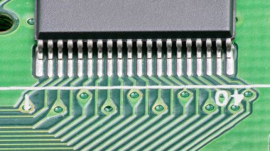 Devre kartına detaylı bir bakış metal bağlantıları ve basılı bağlantıları ortaya çıkarıyor, bir teknoloji tesisinde elektronik montajın karmaşıklığını gösteriyor.