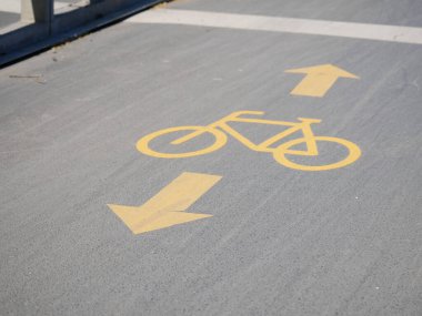 Şehir parkında belirlenmiş bisiklet yolu boyunca bisikletçileri yönlendiren sarı işaretleri temizleyin. İyi korunan yol güvenliği arttırır ve aydınlık bir günde açık hava aktivitesini teşvik eder..