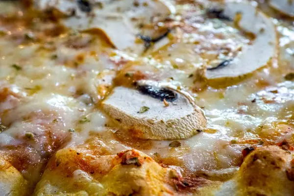 Lezzetli pizza, üzerinde dilimlenmiş mantarla birlikte bol miktarda eritilmiş peynir, taze pişmiş ve sıcak bir toplantıda veya yemekte eğlenmeye hazır..