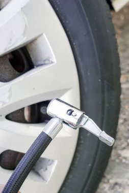 Lastik şişirici ile şişiriliyor. Lastik şişirme aleti siyah ve gümüş.