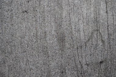 Gri beton bir yüzeye yakından bakmak doğal aşınmanın oluşturduğu eşsiz doku ve desenleri sergiliyor. Yüzey, çevresel faktörlerin zaman içindeki etkisini göstermektedir..