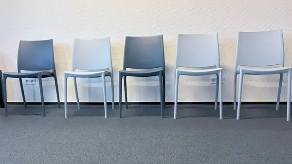 Üst üste dizilmiş beş modern sandalye, temiz, minimalist bir dizaynla bir doktorun ofisindeki modern iç mekanları ön plana çıkarıyor ve.