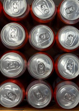 Soda kutuları düzgün bir şekilde düzenlenir, metalik üstleri ve parlak renkleri sergilenir. Düzenlemeler, sıcak bir günde bir kutlama ya da açık havada toplanmayı işaret ediyor..