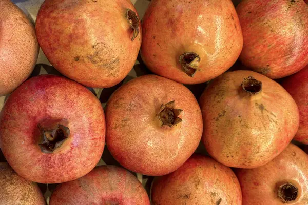 Olgun nar koleksiyonu bir pazarda güzelce düzenlenir. Kırmızı ve pembe renkleri çarpıcı, tazelik ve kaliteyi gösteriyor. Bu görüntü alıcıları çeker.