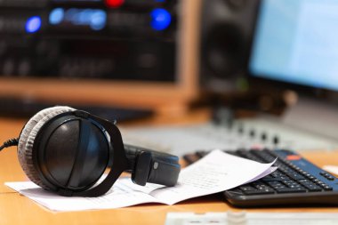 Müzik stüdyosunun arka planında bir klavye bulunan kulaklıklar, yaratıcılık ve ses üretimi atmosferini gözler önüne seriyordu..