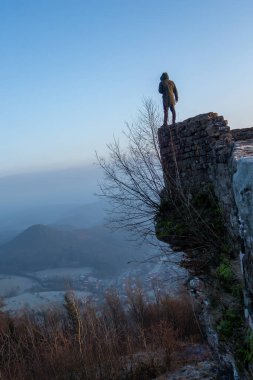 Güneş doğarken antik bir taş yapıya tünemiş bir figür, sis dolu bir vadiye bakıyor. Majestic tepeleri yükseliyor, dinginliği arttırıyor, sabahın erken saatlerinde atmosferi..