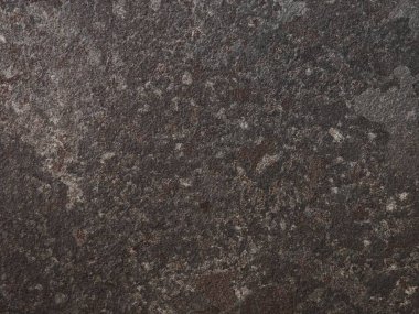 Yüzeyde, düşük ışık koşullarında kayanın doğal güzelliğini vurgulayan, zaman içinde oluşan koyu gölgelerin ve karmaşık desenlerin zengin bir karışımı sergileniyor..