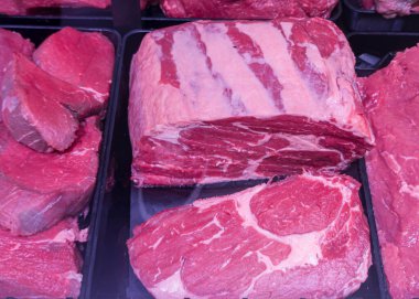 Bir kasapta çeşitli sığır kesimleri düzgün bir şekilde düzenlenir. Görünür mermerli canlı kırmızı et sergilenir. Gösterge kaliteyi ve tazeliği vurguluyor, müşterileri çekiyor.