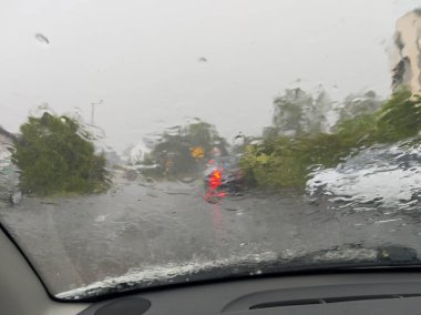 Bardaktan boşanırcasına yağan yağmur, banliyödeki bir yol manzarasını engelliyor. Arabalar yağmurda görülebilir ve fırtına zorlu bir sürüş durumu yaratır..