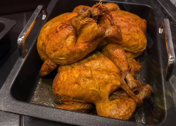 Zengin altın renginde kızarmış tavuklar servis tepsisinde yığılır ve lezzetli aromalar yayar. Bu yemek muhtemelen açık büfe yemeğinin bir parçası, aç lokantalara servis etmeye hazır..