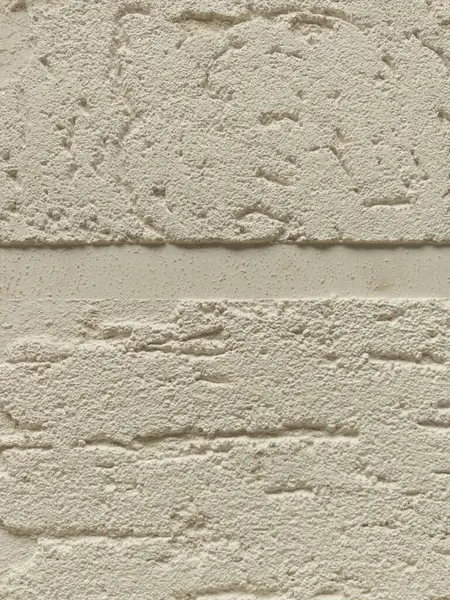 Kalıplı alçı duvarda ince oyuklar ve desenler var. Görsel ilgi yaratıyor. Işık, nötr rengin eşsiz dokusunu ve gölge varyasyonlarını vurguluyor..