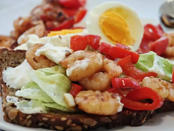 Lezzetli bir açık sandviçte karides, taze sebze ve tam tahıllı ekmeğin üzerinde haşlanmış yumurta bulunur. Bu yemek sağlıklı bir kahvaltı ya da hafif bir öğle yemeği için mükemmel..