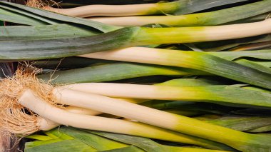 Taze pırasalar yerel bir markette üst üste yığılır, canlı yeşil bluzları ve sert beyaz sapları sergilenir, sonbaharın başlarında mevsimlik sebze arayan müşterileri cezbeder..