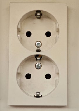 A white electrical outlet featuring two sockets is mounted on a wall. The installation appears clean with visible screws, suitable for powering various devices.