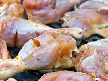 Bir parça tavuk kanadı pişiriliyor. Kanatlar baharatlarla kaplı ve ızgarada