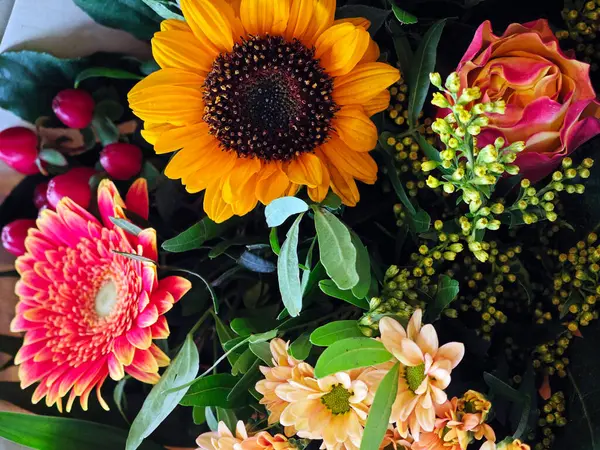 Canlı bir buket ayçiçekleri, gerberalar ve taze yeşillikle sıralanmış güllerden oluşur. Bu çiçek aranjmanı doğanın gündüz güzelliğini yakalar..