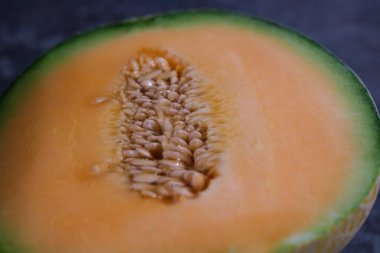 Olgun bir kavun, tatlı portakal etini ve tohum kümelerini ortaya çıkararak ikiye bölünür. Canlı renkler tazeliği gösteriyor, yaz meyve salatası veya atıştırmalıkları geliştirmek için ideal..