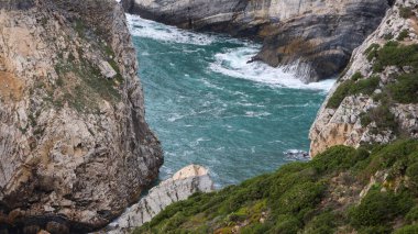Portekiz 'in güney kıyısındaki kayalık bir sahilde bir deniz ve kayalıkların dikey görüntüsü.