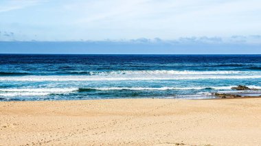 Deniz dalgaları ve mavi gökyüzü olan güzel sahil