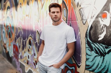 Grafiti duvarının yanında sakallı yakışıklı bir genç adam portresi.