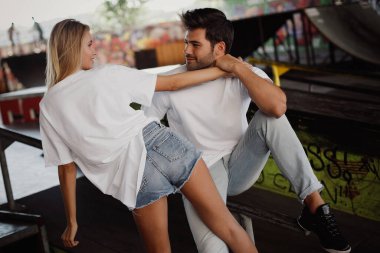 Genç bir çiftin portresi kaykay parkındaki duvarın yanında birbirine aşık.