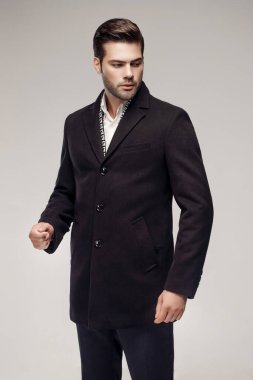 Yakışıklı bir Avrupalı model stüdyoda şık bir koyu renk ceket giyiyor..