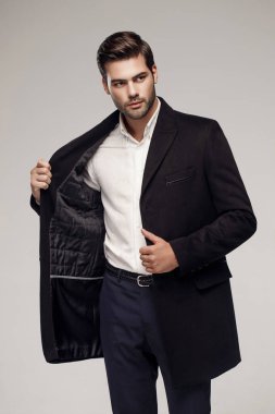 Yakışıklı beyaz model stüdyoda zarif bir ceketle poz veriyor. 