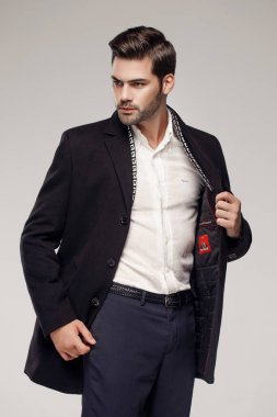 Yakışıklı beyaz model stüdyoda zarif bir ceketle poz veriyor. 