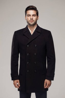 Yakışıklı bir Avrupalı model stüdyoda şık bir koyu renk ceket giyiyor..