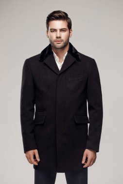 Yakışıklı bir Avrupalı model stüdyoda şık bir koyu renk ceket giyiyor..