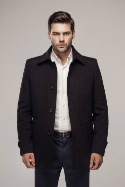 Yakışıklı beyaz model stüdyoda zarif bir ceketle poz veriyor. 