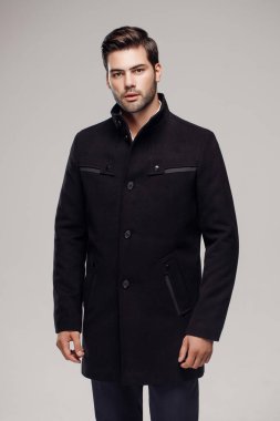 Yakışıklı bir Avrupalı model stüdyoda şık bir koyu renk ceket giyiyor..