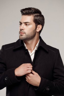 Yakışıklı Avrupalı model şık, koyu renk ceket giyiyor ve stüdyoda poz veriyor. 